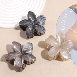 Three elegant marble-textured plumeria hair claws in charcoal, taupe, and cream colors