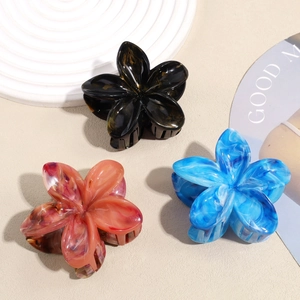 Detailed close-up of marble pattern acetate flower hair clips in black, pink, and blue