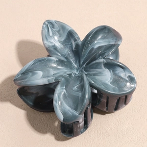 Detail of marble pattern hair claw clip with acetate flower design and glitter finish