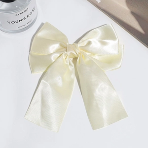 Detailed view of elegant double-layered cream satin bow hair clip with smooth silk texture