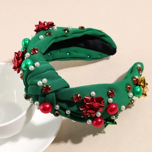 Detailaufnahme von grünem Weihnachts-Haarreif mit roten Schleifen und Glitzersteinen