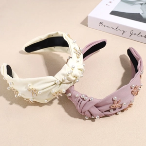 Eleganter Haarreif mit Perlen und goldenen Schleifenakzenten in Creme und Lavendel