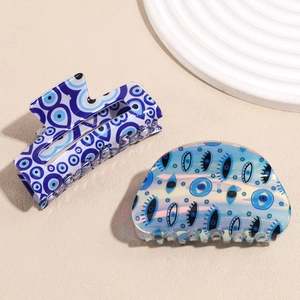 Vintage rectangular hair claw set with blue evil eye motifs on a textured white plate