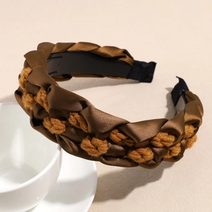 Detail of retro braided fabric headband in brown and yellow with non-slip inner teeth