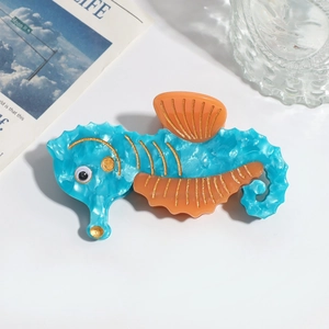 Close-up of a seahorse hair claw clip made of blue acetate with orange glitter details