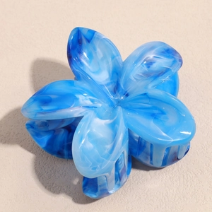 Detailed top view of blue marble pattern flower hair claw with elegant glossy texture