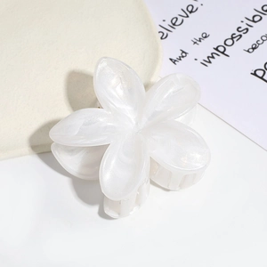 Macro detail of pearlescent white flower hair claw clip with elegant marble finish
