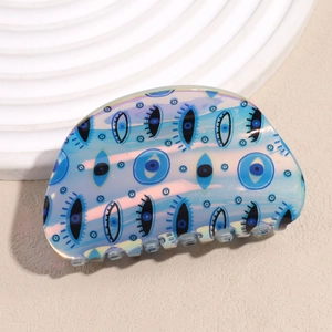Detail of blue acetate hair claw clip featuring evil eye patterns and glossy finish