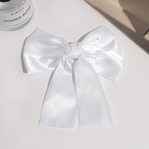 Detailed view of white satin double-layered bow hair clip with glossy silk texture