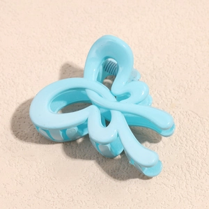 Detail of light blue bow hair claw clip with glossy resin finish and metal spring