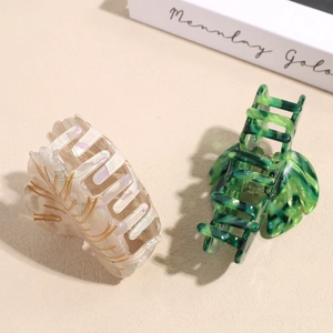 Elegant leaf-shaped acetate hair claws in cream marble and emerald green patterns