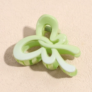 Macro shot of light green curved hair claw clip with glossy finish and metal spring