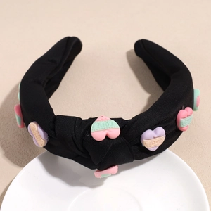 Detailansicht eines breiten Stoffstirnbands mit bunten 3D-Herzanhängern und LOVE-Prägung