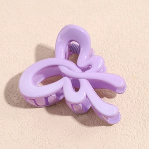 Macro shot of a matte lavender bow hair claw clip showing a purple metal spring