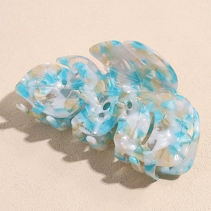 Detail of leaf-shaped acetate hair claw clip with blue and beige marble texture