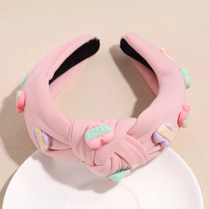 Detail eines rosa Stoffstirnbands mit bunten Harzherzen und LOVE-Schriftzug für Damen