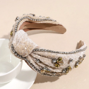 Detail of baroque knotted beige velvet headband with rhinestones and sequins on a mug
