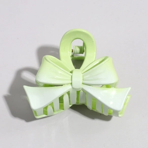 Detailed view of a mint green plastic bow hair clip with a metallic spring mechanism