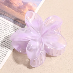 Detail view of a lavender translucent flower hair claw clip on a minimalist beige surface