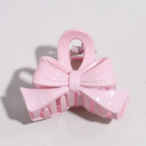 Detailed view of the light pink bow-shaped hair clip with smooth glossy finish and comb teeth