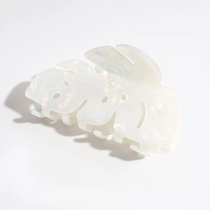 Macro detail of leaf-shaped hair claw in iridescent white acetate with pearl texture