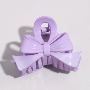 Detail view of a matte purple bow hair clip with a durable metal spring closure