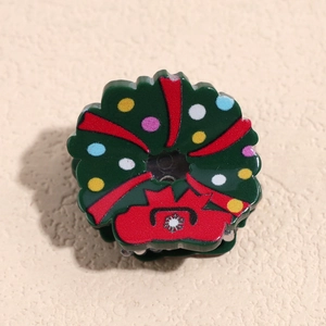 Vue macro d'une pince à cheveux en résine de Noël avec nœud rouge et points colorés
