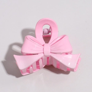 Detail view of pink bow hair clip showing glossy resin material and metal spring