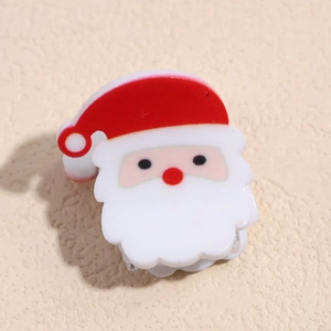 Détail d'une pince à cheveux Père Noël en résine sur un fond texturé beige doux