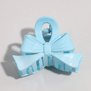 Macro view of a light blue bow-shaped hair clip made of glossy resin with metal spring