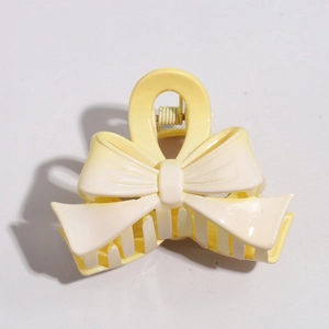 Detailed close-up of a light yellow cream bow hair clip with textured matte finish