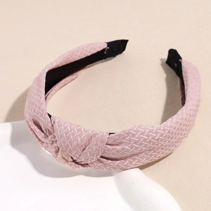 Détail d'un serre-tête rose avec nœud, tissu texturé à chevrons et doublure antidérapante