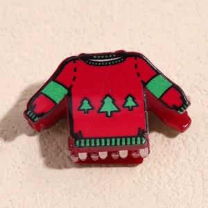 Détail de la pince à cheveux pull de Noël rouge avec motifs de sapins festifs