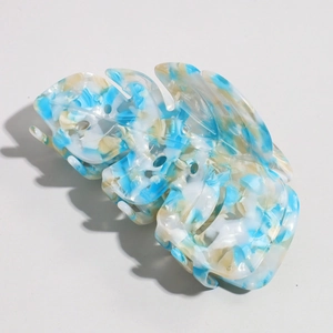 Detailed macro view of tropical leaf acetate hair claw with blue marble stone texture