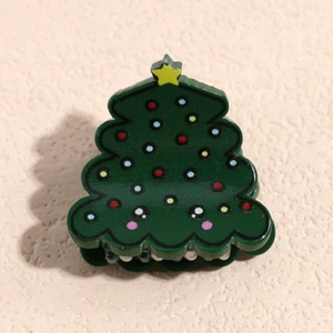 Détail d'une pince à cheveux en résine en forme de sapin de Noël avec points colorés