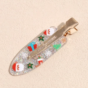 Close-up of glittery Christmas hair clip with Santa and snowflake motifs on gold metal base