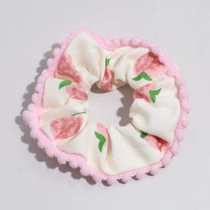 Detail von weißem Haargummi mit Erdbeerdruck und rosa Pompons am Rand verziert