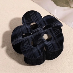 Detail view of black flocked checkered plumeria hair claw clip with velvet texture