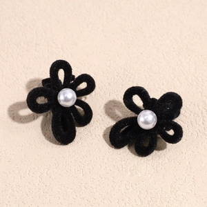 Dettaglio di eleganti fermagli per capelli a fiore in velluto nero con perla centrale