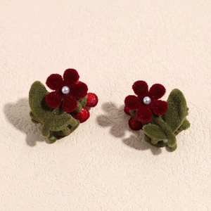 Dettaglio di fermaglio per capelli a fiore rosso con perla bianca e decoro bacche