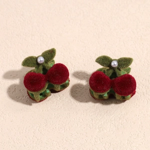 Dettaglio delle clip per capelli a ciliegia in velluto rosso e verde con perla