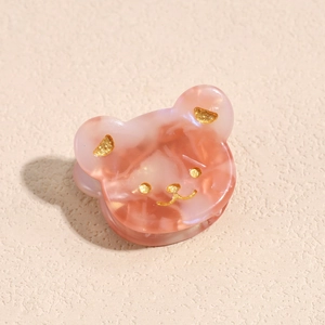 Vista macro di una mini molletta per capelli in acetato rosa a forma di orsetto carino