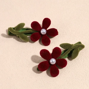 Dettaglio macro di fermagli per capelli a fiori rossi con perle su superficie ruvida