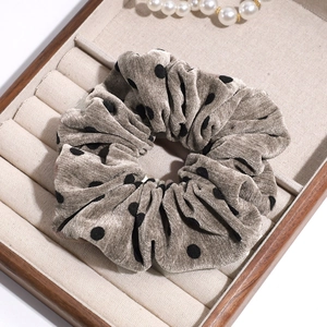 Vintage khaki polka dot corduroy scrunchie displayed on a wooden jewelry tray with pearls