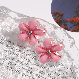 Detailed close-up of pink camellia hair claws with rhinestones and golden metal clips