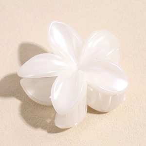 Détail macro d'une pince à cheveux Plumeria blanche avec finition nacrée crème