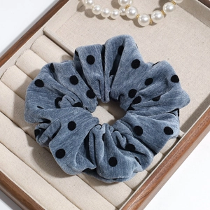 Detailed view of grey velvet polka dot scrunchie on a decorative jewelry display tray