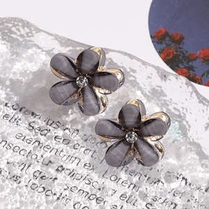 Close-up of grey-purple camellia stud earrings with rhinestones and gold-tone finish