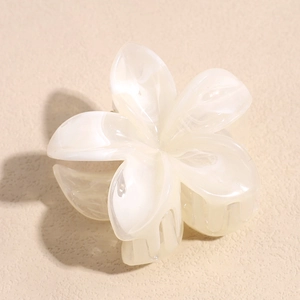 Gros plan d'une pince à cheveux fleur de frangipanier avec texture marbrée perle
