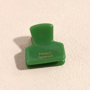Dettaglio della pinza per capelli verde scuro con scritte dorate fatta a mano